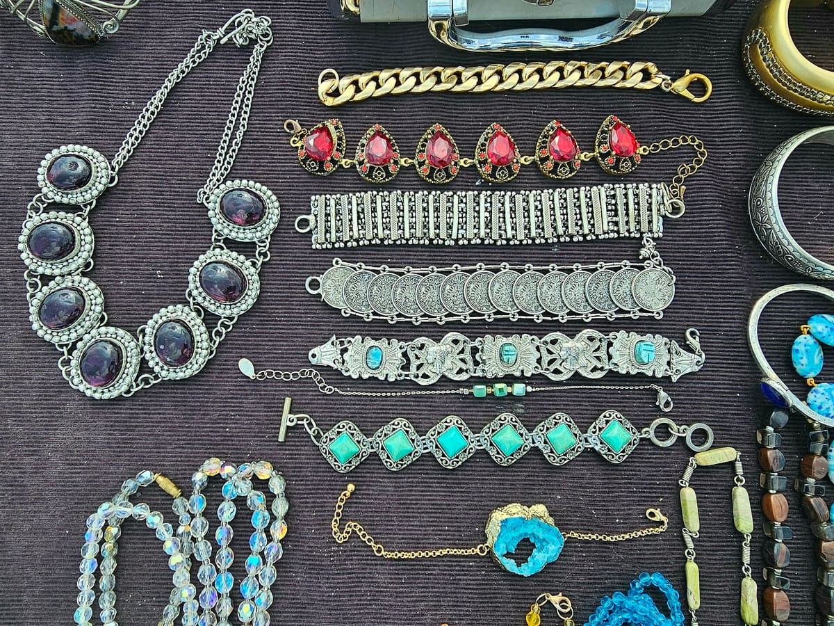 Vintage costume jewellery laid out on dark cloth, including bead necklaces and stone-set bracelets