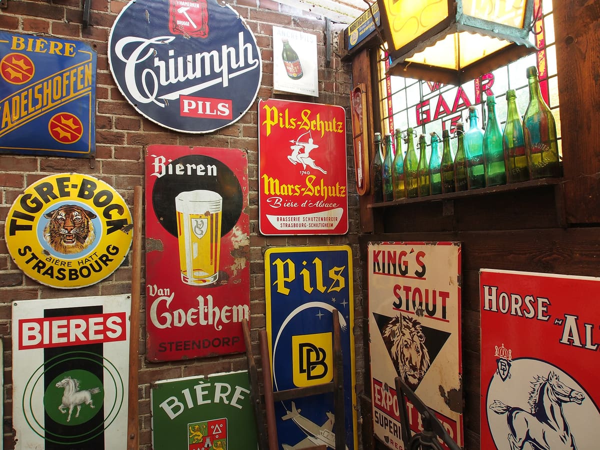 A brick wall covered in old enamel beer advertising signs