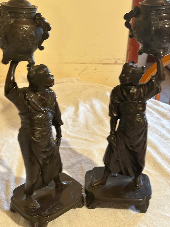 The pair of Mori Homei bronze boys side by side, each holding a koro above his head